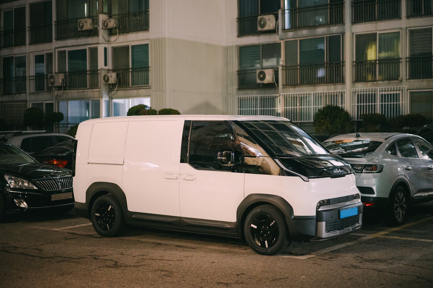 Valkoinen pakettiauto pysäköitynä kaupunkialueen parkkipaikalle.